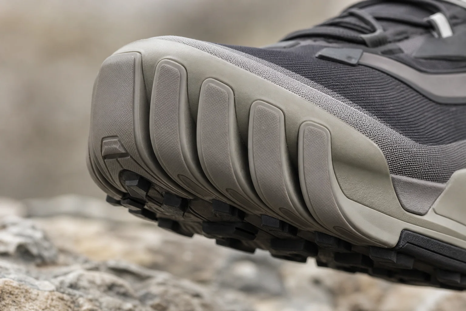 Close-up detail of a trail shoe's rock plate and forefoot protection during a downhill section