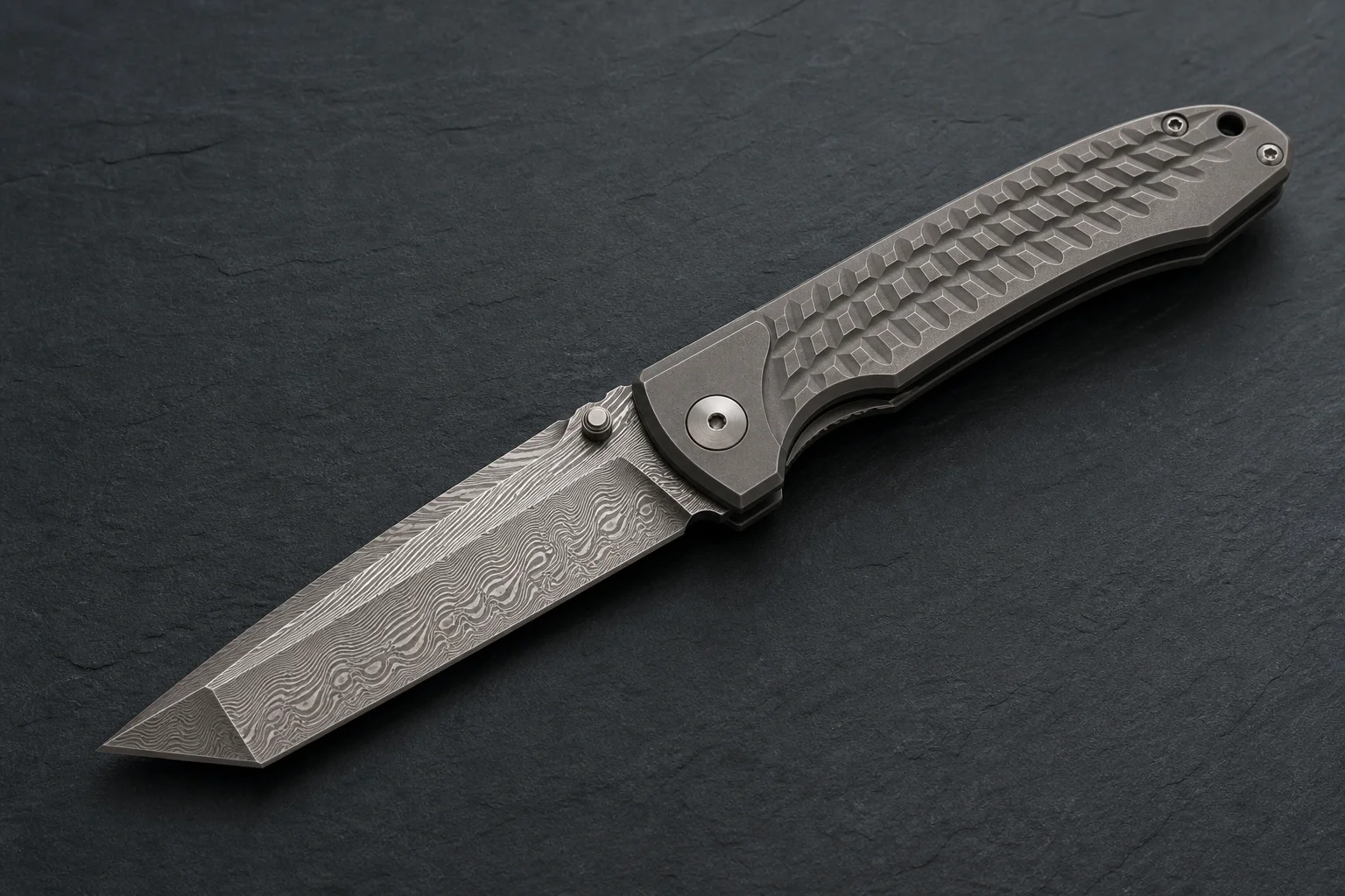 Premium folding knives with titanium handles and Damasteel blades on a dark slate surface