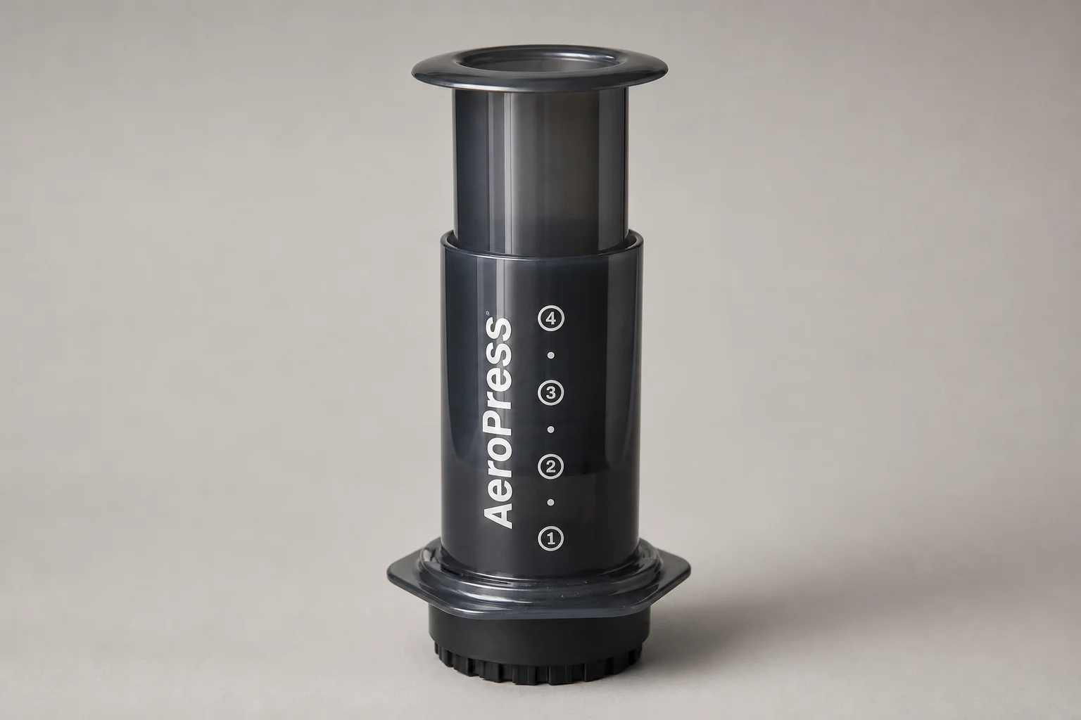 Quattro caffettiere economiche: AeroPress, Chemex, Moka Express e Bodum Chambord disposte su una superficie in cemento