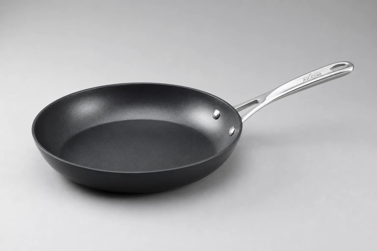 Sartenes antiadherentes tradicionales de PTFE y cerámica colocadas una al lado de la otra sobre una superficie de hormigón