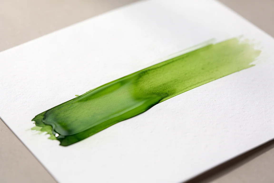 Échantillon d'encre vert éclatant avec irisation visible sur papier blanc