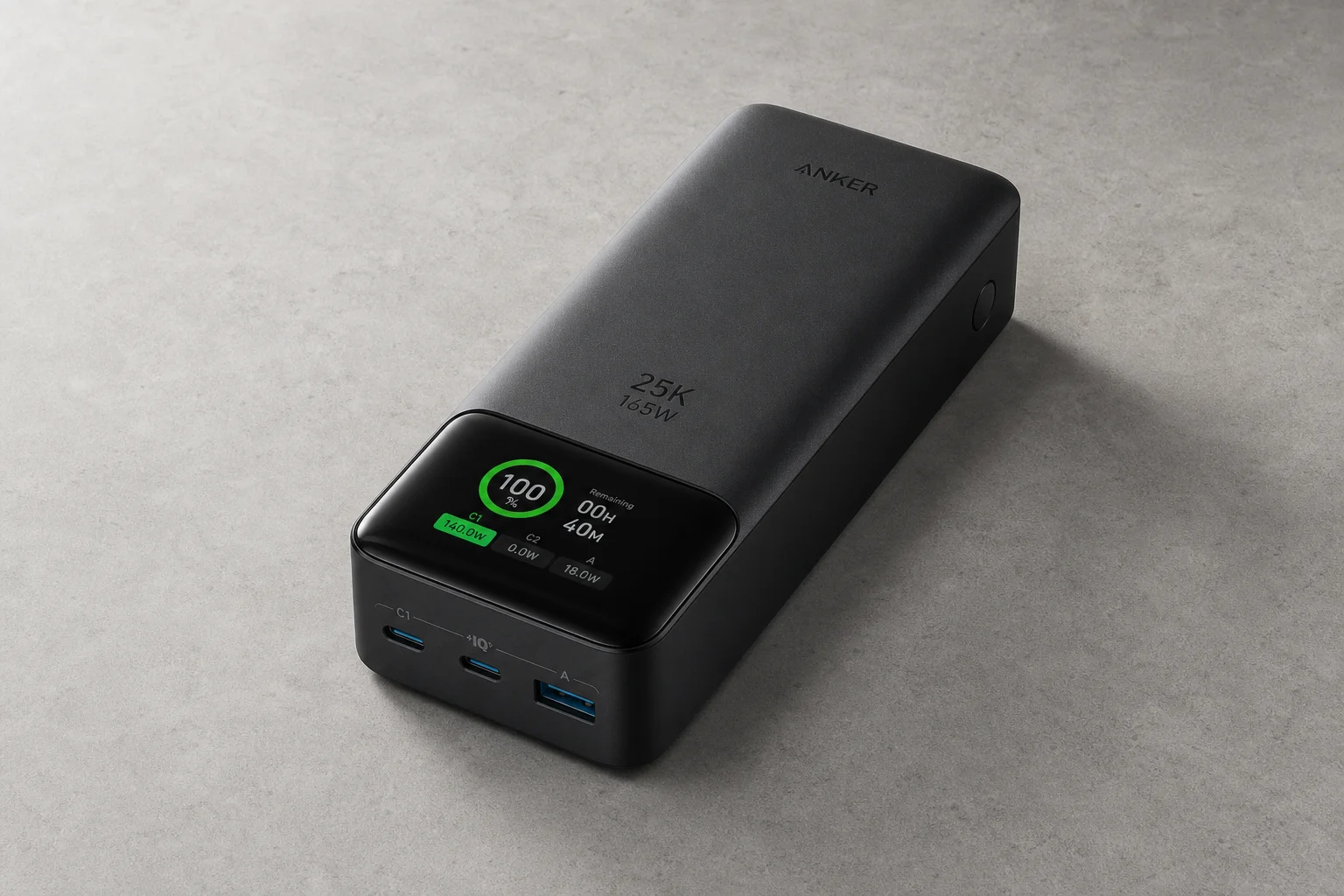 放置在霧面水泥地上的 Anker 25K 筆電行動電源，數位顯示螢幕清晰可見