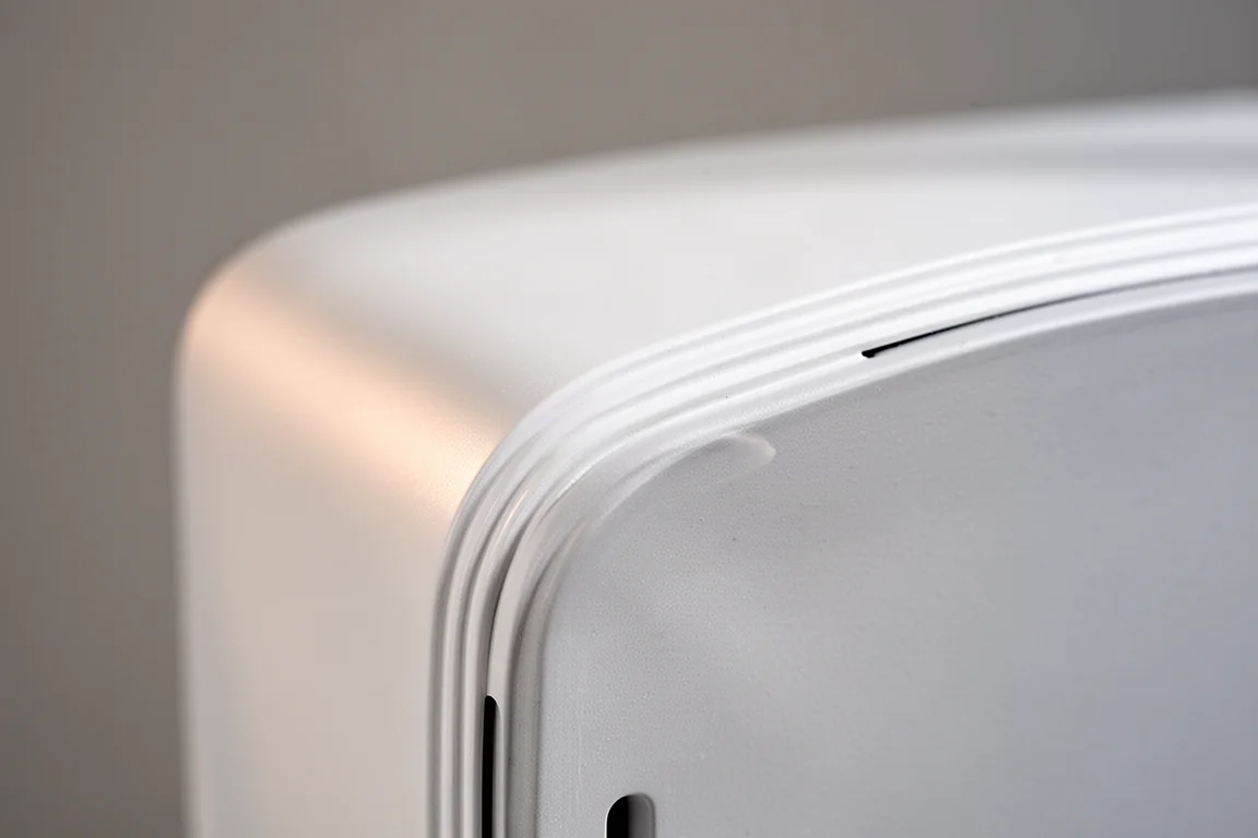 Gros plan sur le bord d'un coffret d'enceinte blanc mat et son évent frontal en fente
