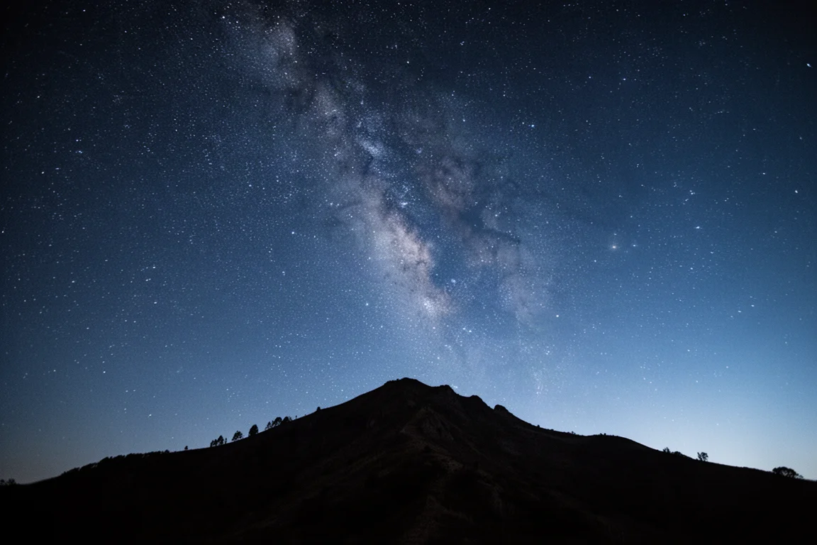 Star-filled night sky above a silhouetted mountain ridgeline