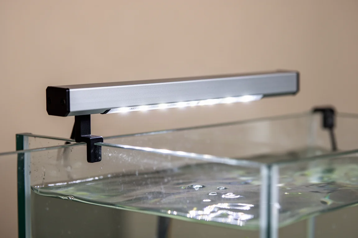 Close view of a slim LED strip resting on the rim of a glass aquarium