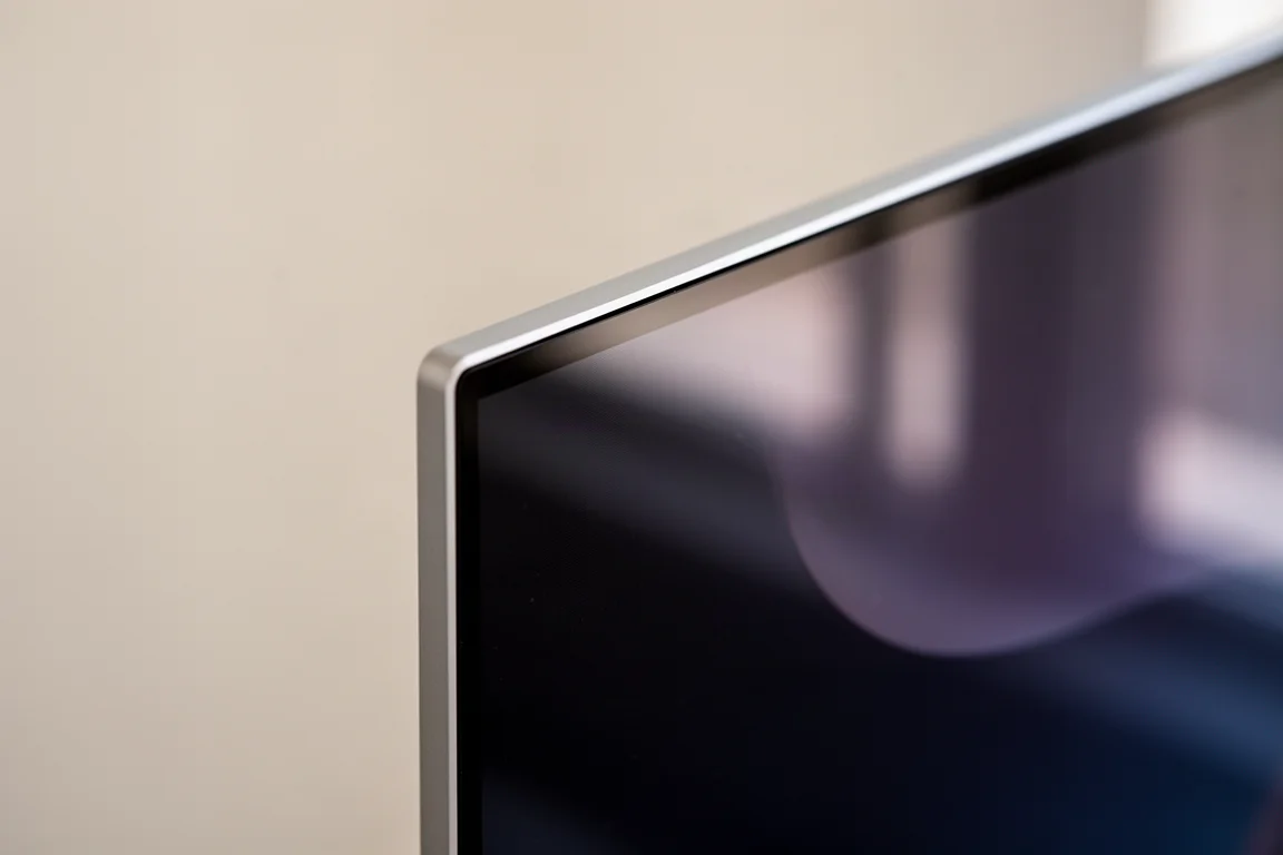 Close-up of a glossy monitor screen edge showing the thin bezel and reflective coating