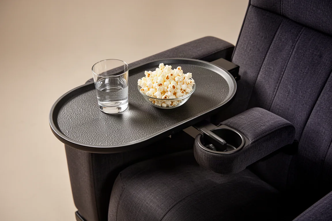 Mesinha de apoio oval estendida do braço de uma poltrona de cinema segurando um copo e pipoca