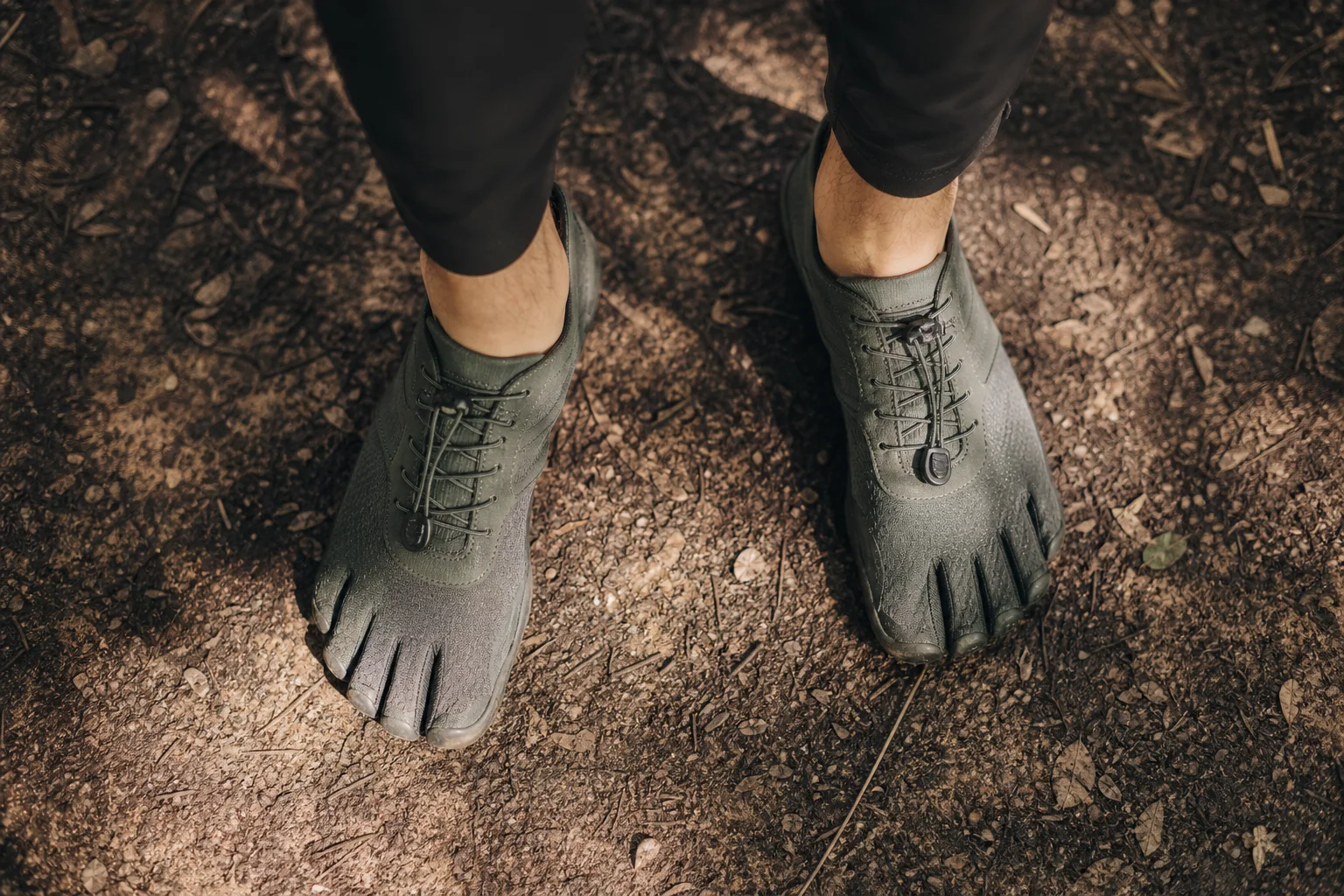 Füße eines Läufers in Barfußschuhen auf einem natürlichen Pfad mit gesprenkeltem Sonnenlicht