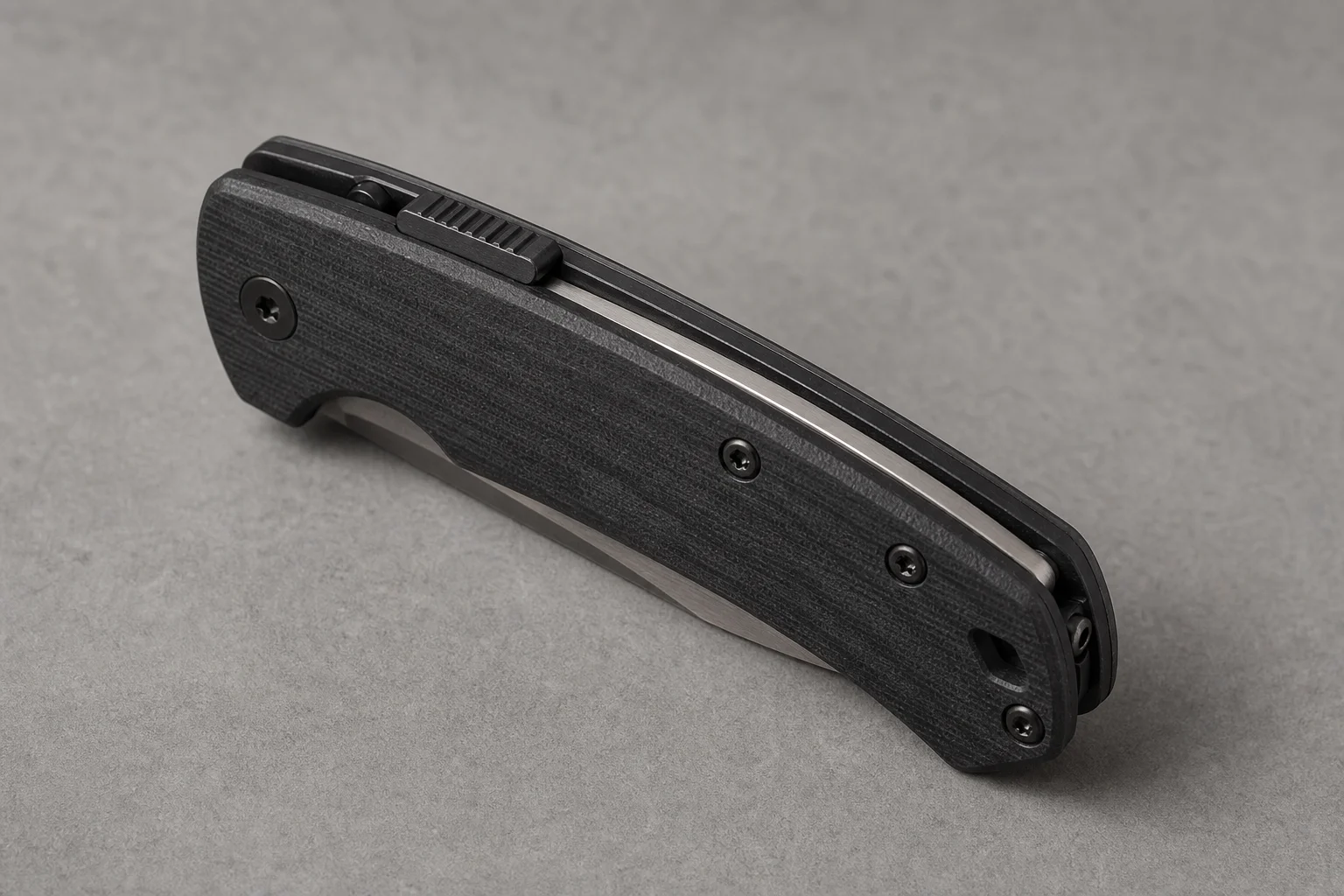 Premium folding knives with titanium handles and Damasteel blades on a dark slate surface