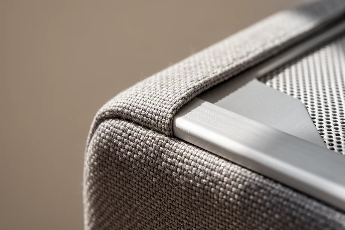 Nahaufnahme von gewebtem Lautsprecherstoff, der auf eine gebürstete Aluminiumkante trifft