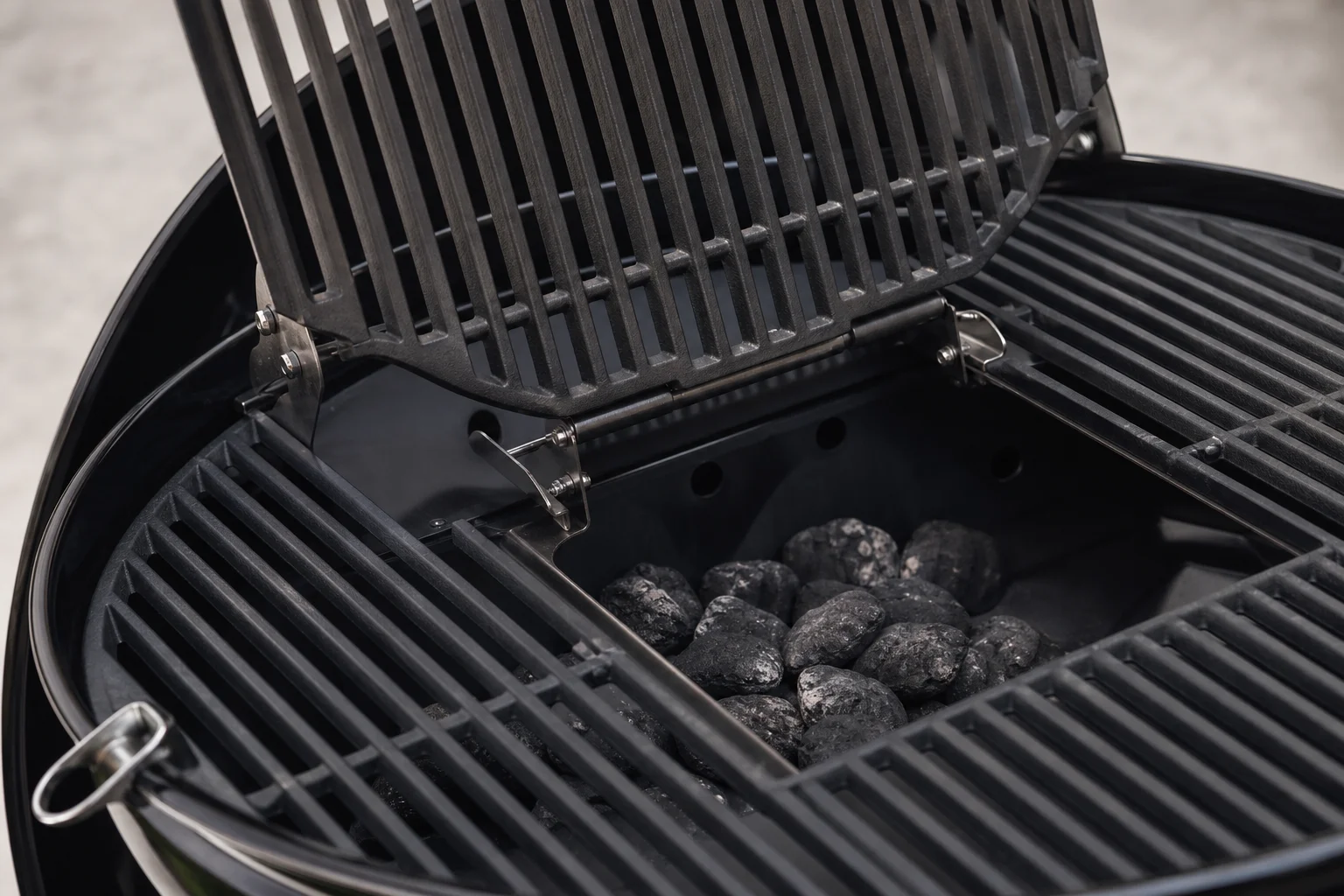 Klappbare Grillroste eines Kugelgrills mit geöffnetem Mittelteil für den Zugang zur Holzkohle