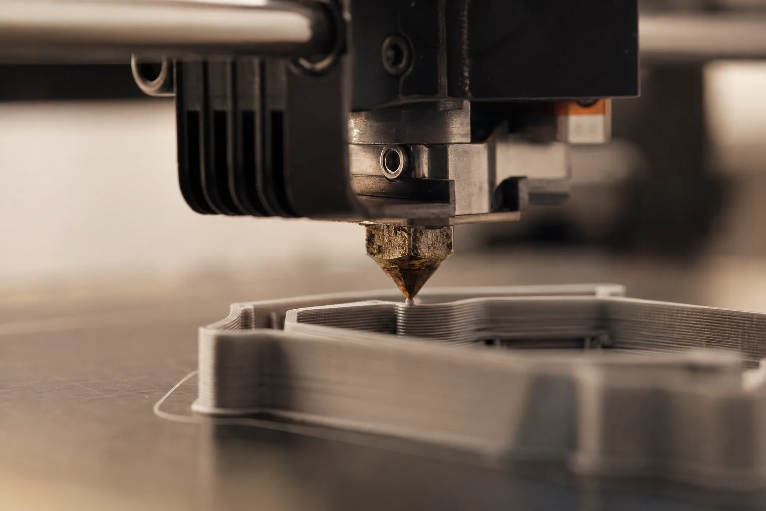 Gros plan sur une buse d'imprimante 3D extrudant du filament sur un plateau d'impression