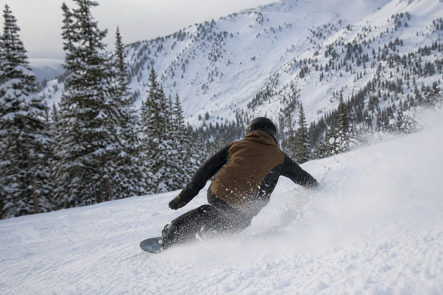 Snowboarder performing a turn with snow spray visible