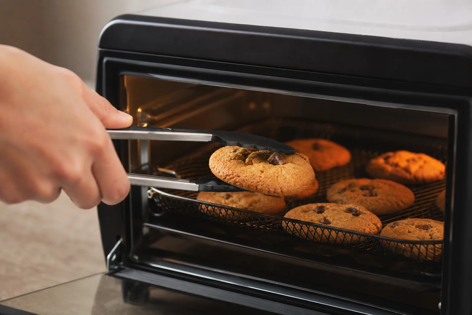 Händer som tar ut en nybakad kaka ur en airfryer-ugn