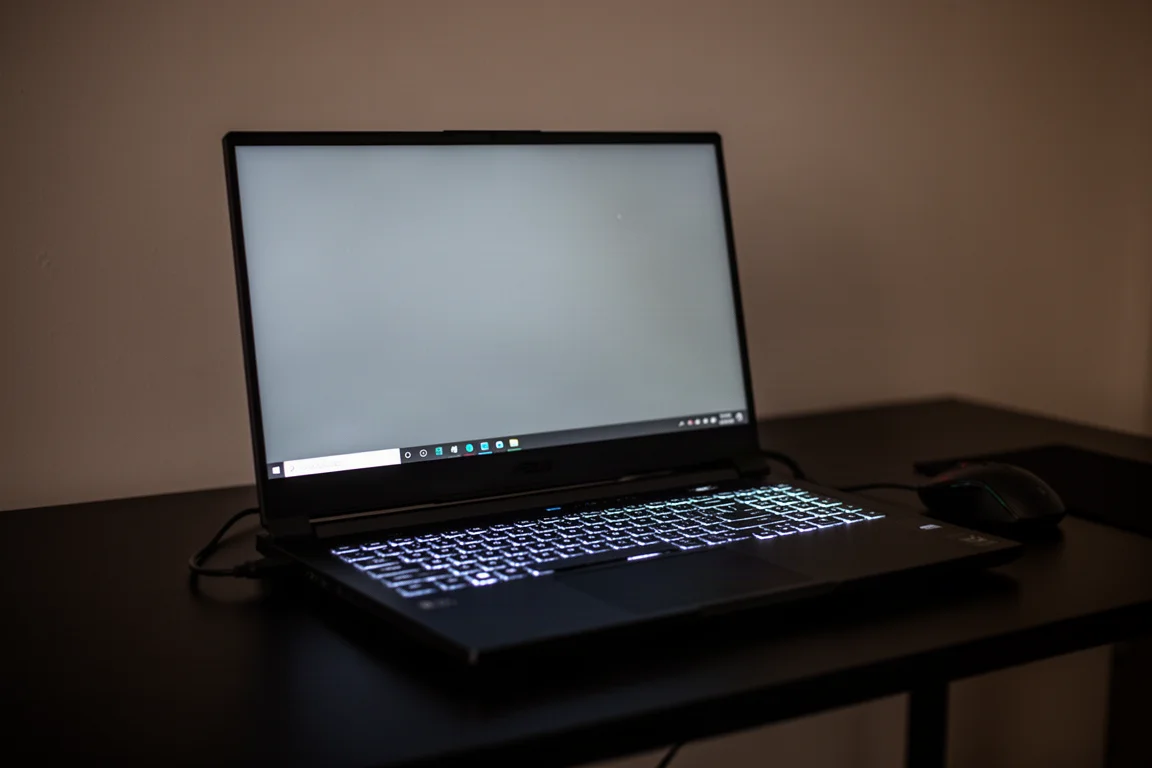Gaming-laptop met verlicht toetsenbord open op een donker bureau in de avond