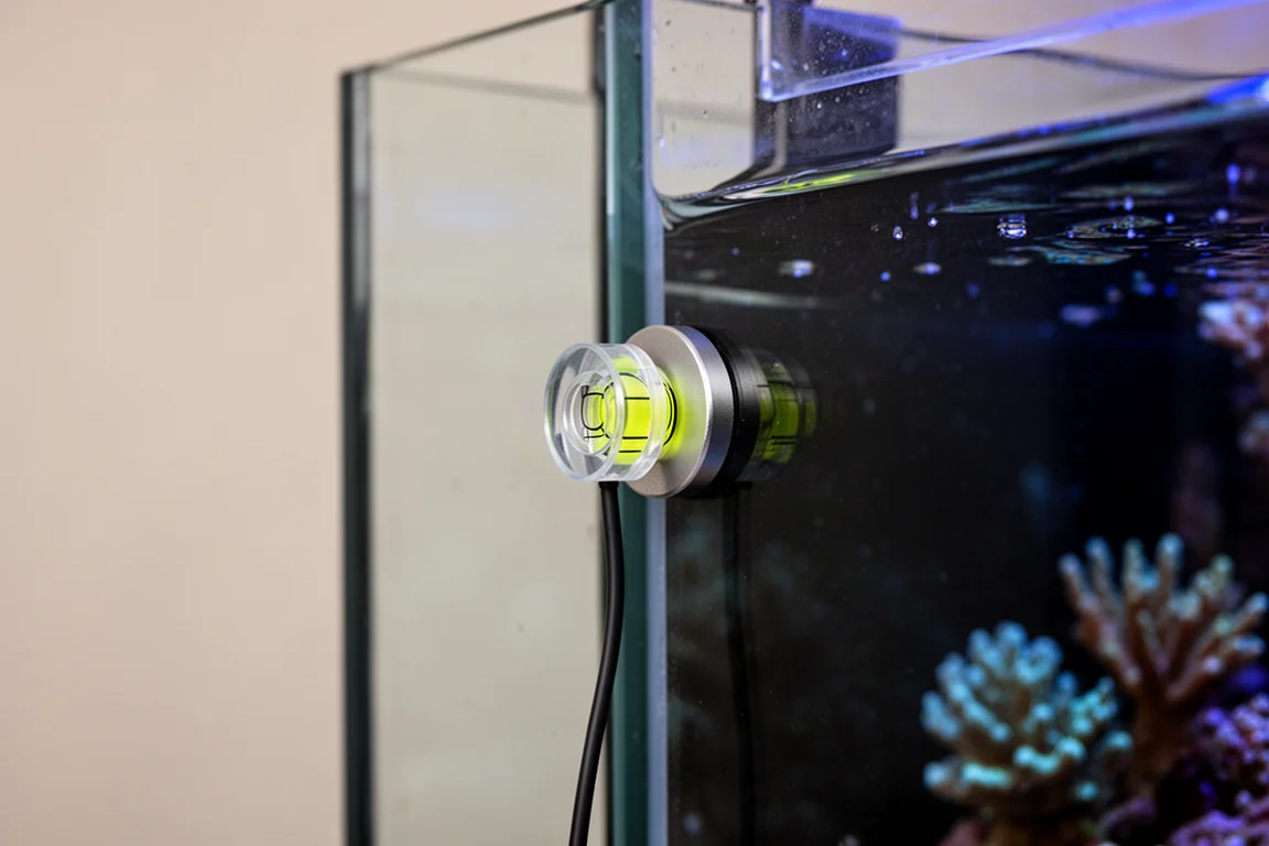 Liten skivformad sensor magnetiskt fäst på akvariets glassida