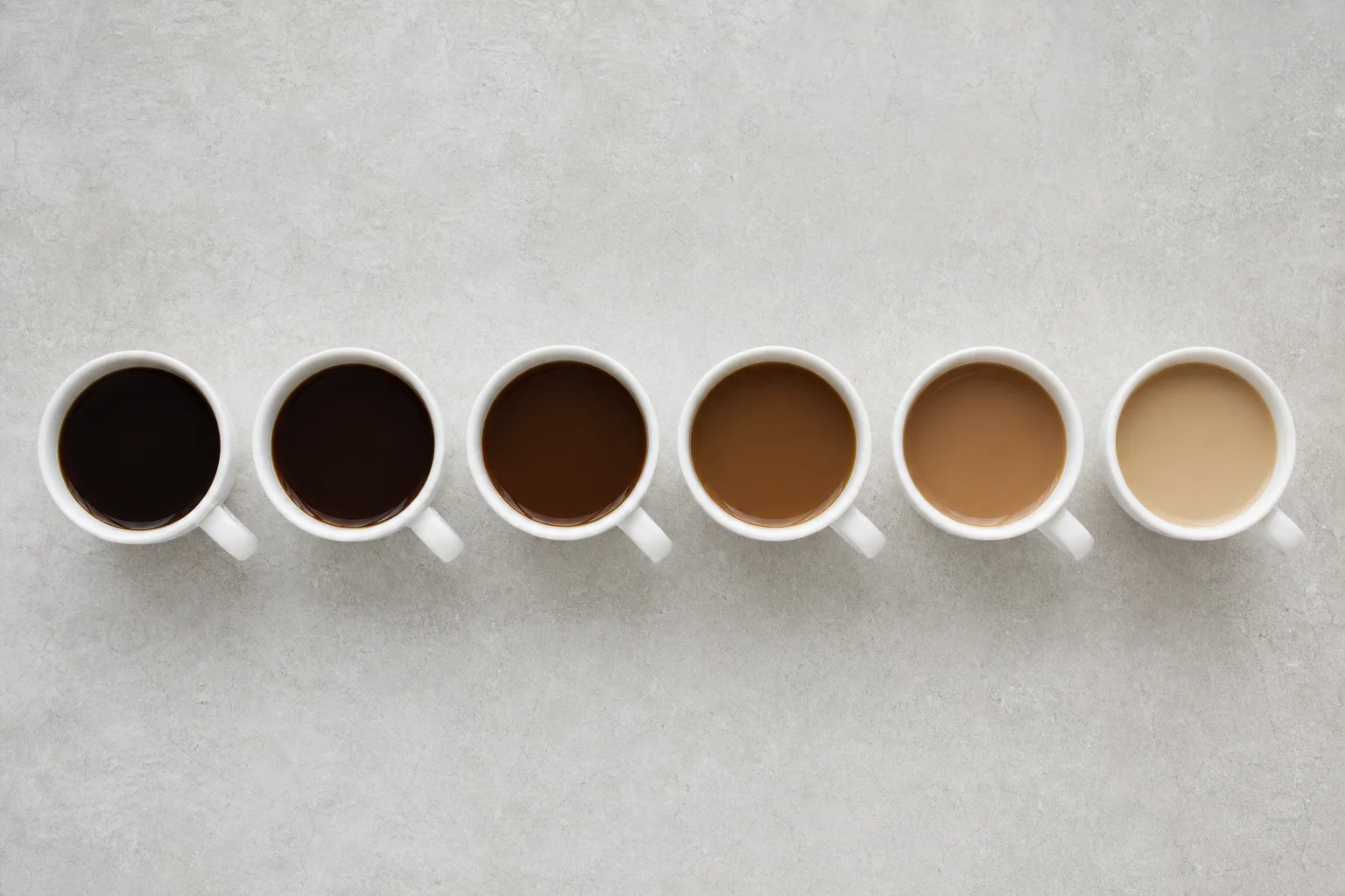 Seis tazas de café preparado de diferentes cafeteras dispuestas para una cata a ciegas