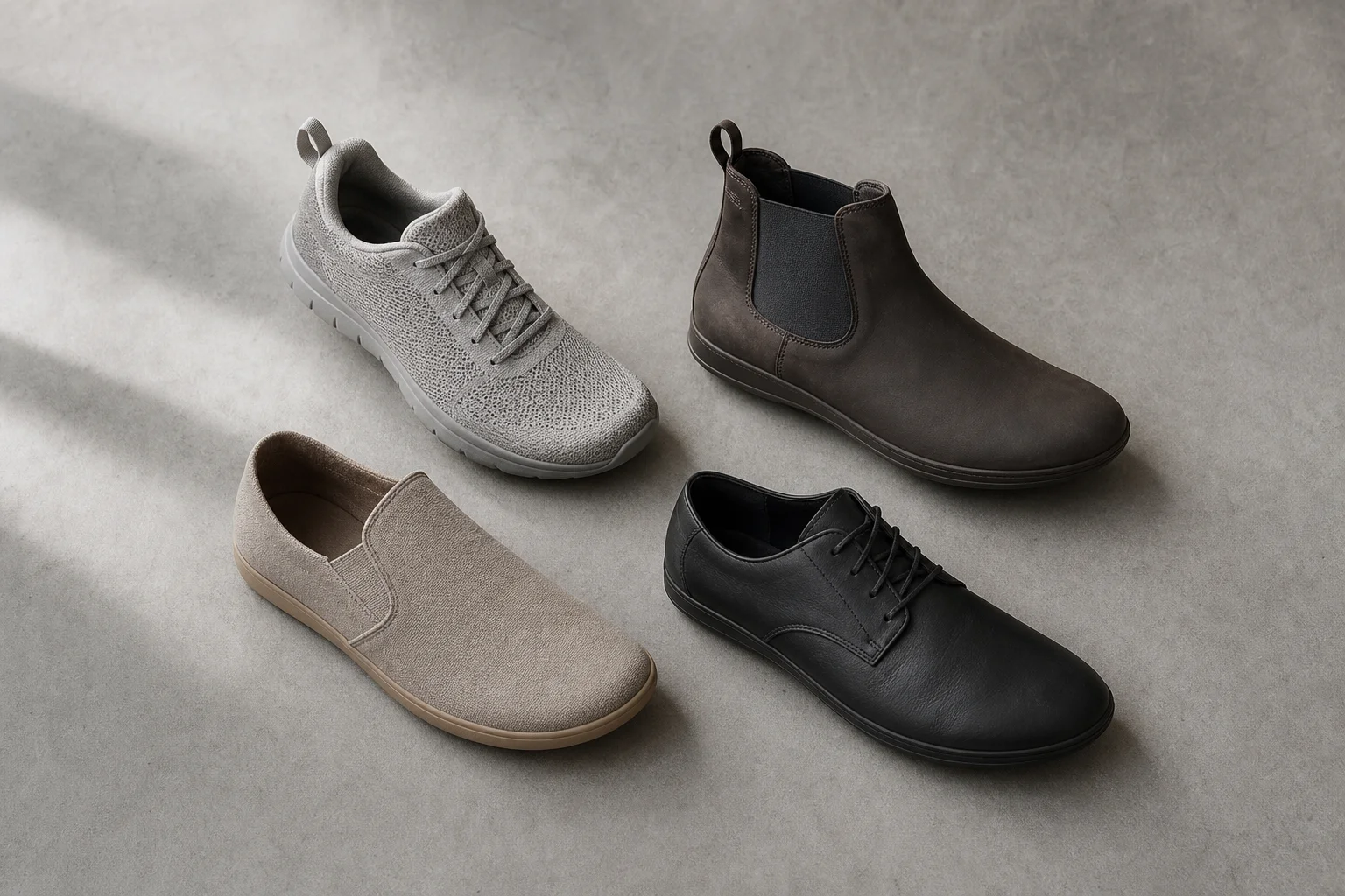 Quattro diversi modelli di scarpe barefoot disposti su una superficie in cemento