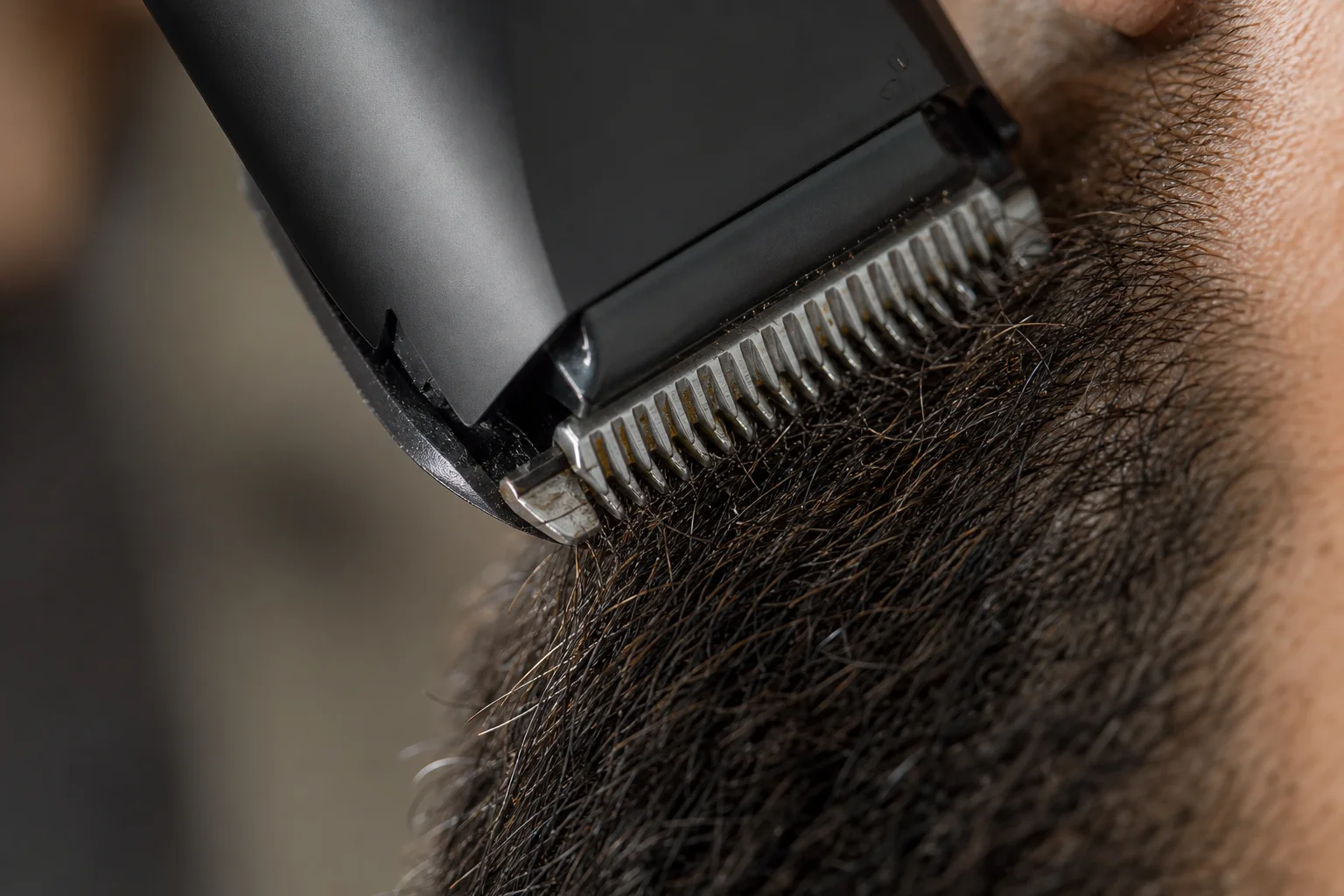 Close-up of trimmer blade cutting through thick beard hair