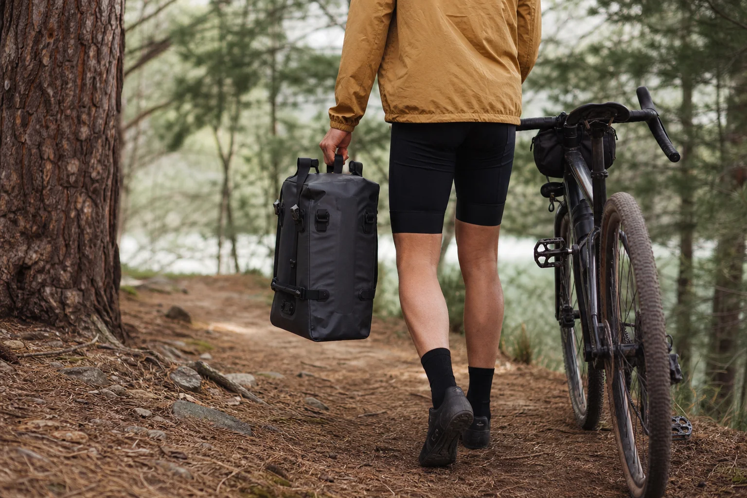 Cyclist carrying pannier bag by hand on a trail
