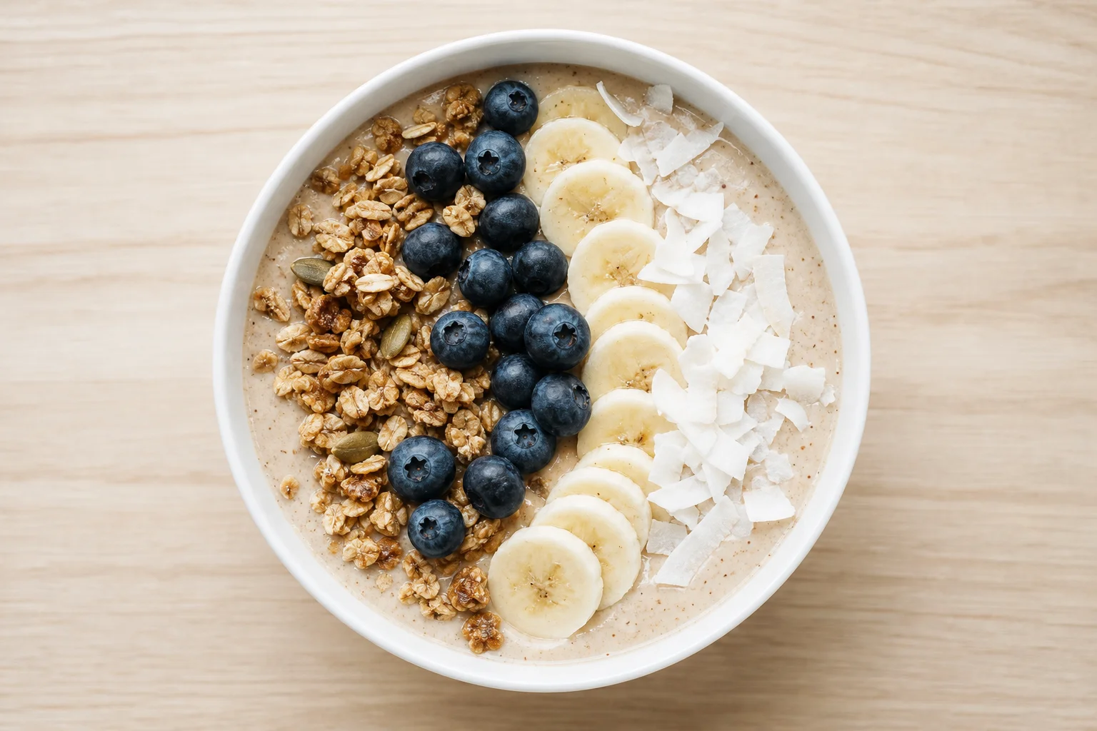 Smoothie bowl topped with granola and fresh berries in a white bowl