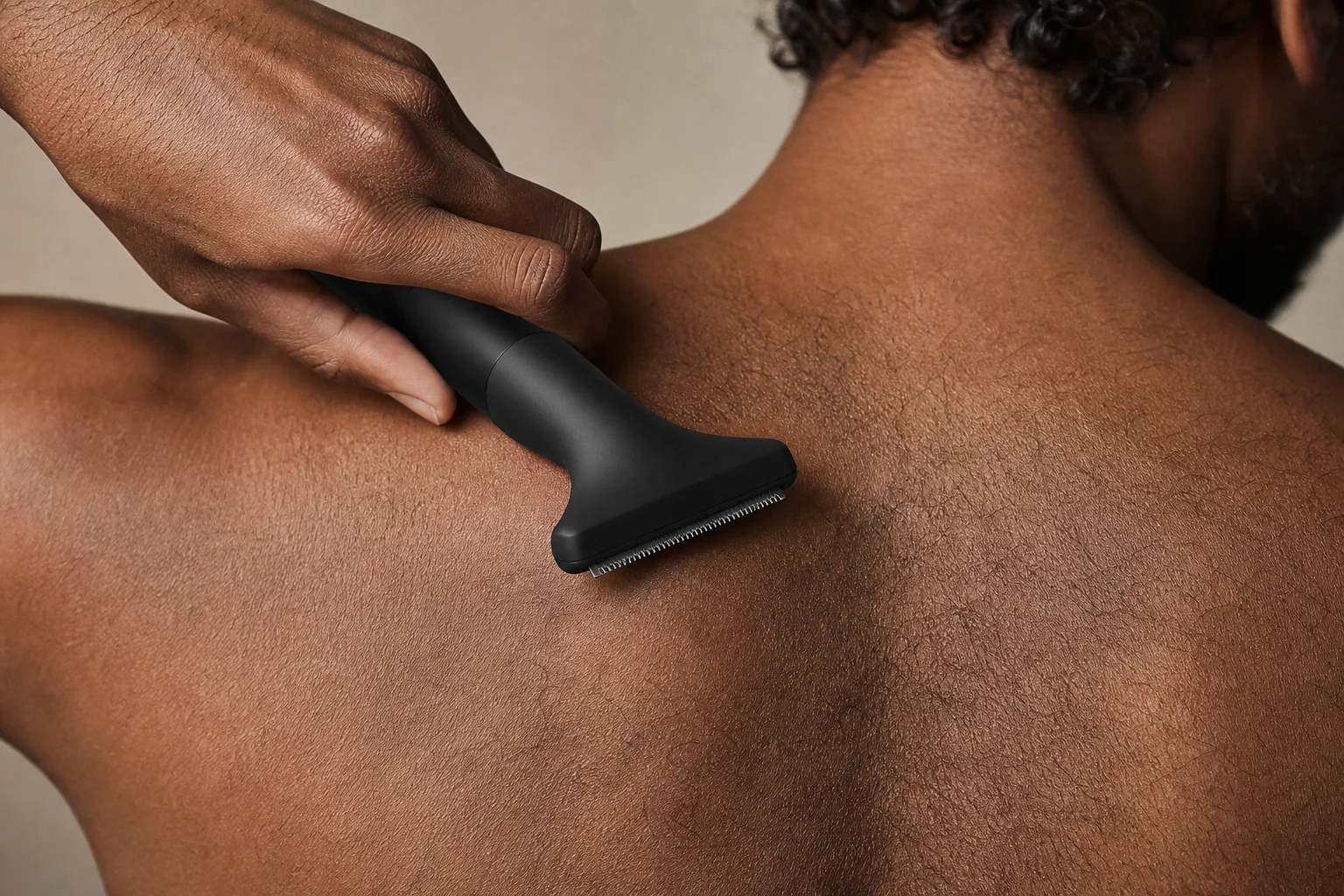 Nahaufnahme eines Bodygroomers mit vertikalem Scherkopf beim Trimmen von Rückenhaaren