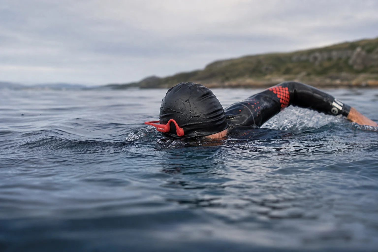 Swimmer in open water wearing waterproof bone conduction headphones