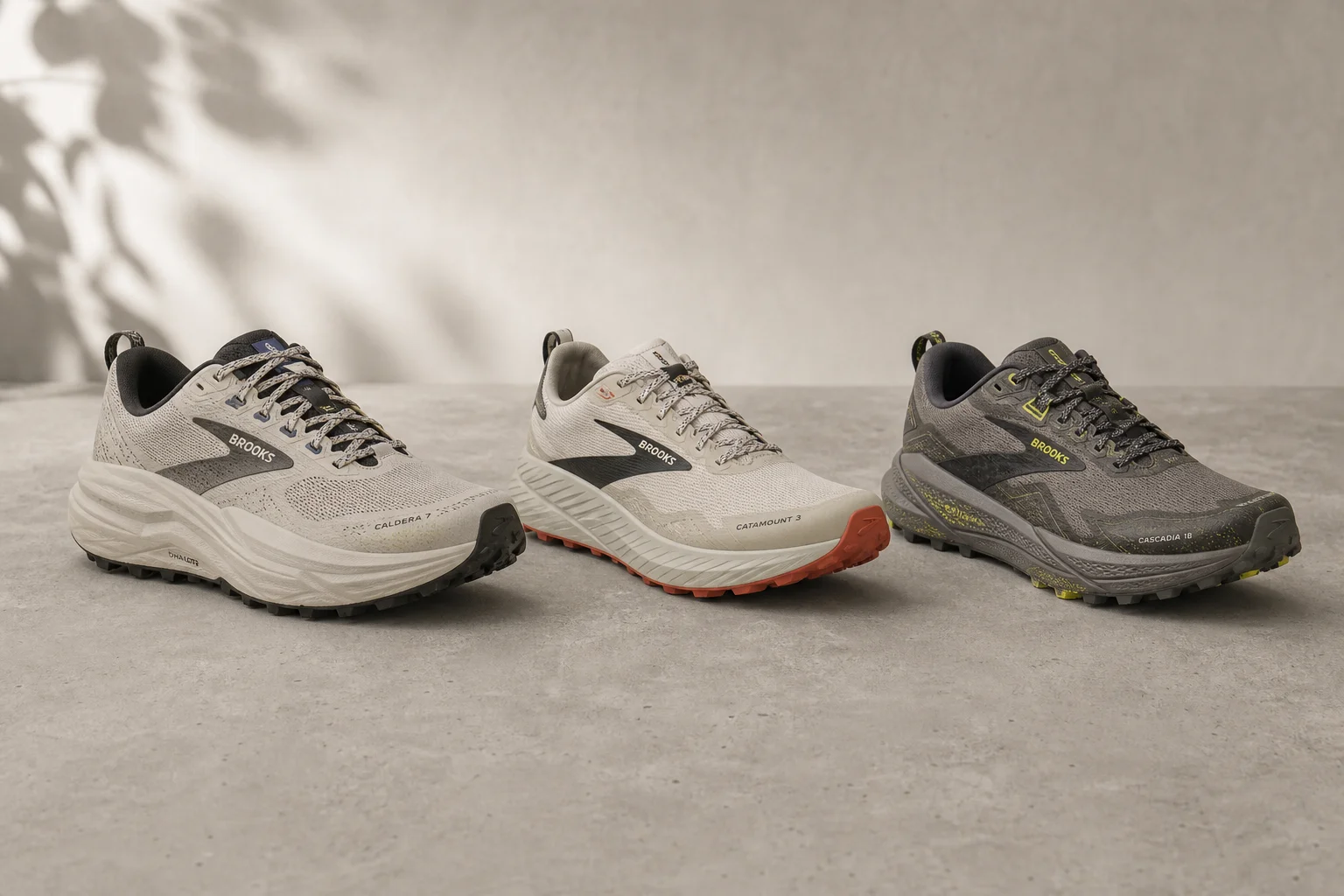 Three Brooks trail running shoes displayed on concrete surface