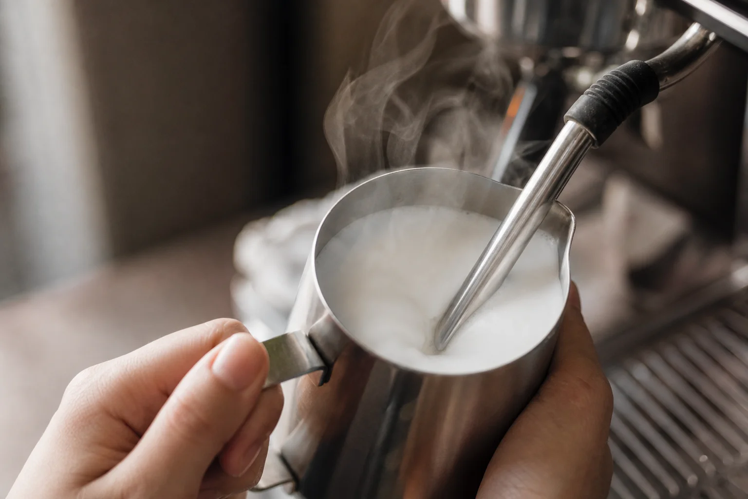 Milk being frothed with steam wand creating microfoam
