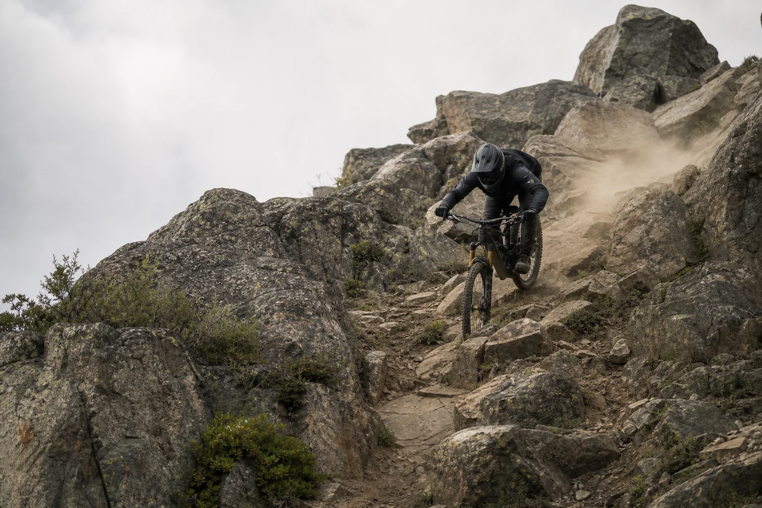 Mountainbiker fährt schnell einen steilen, felsigen Downhill-Abschnitt hinunter