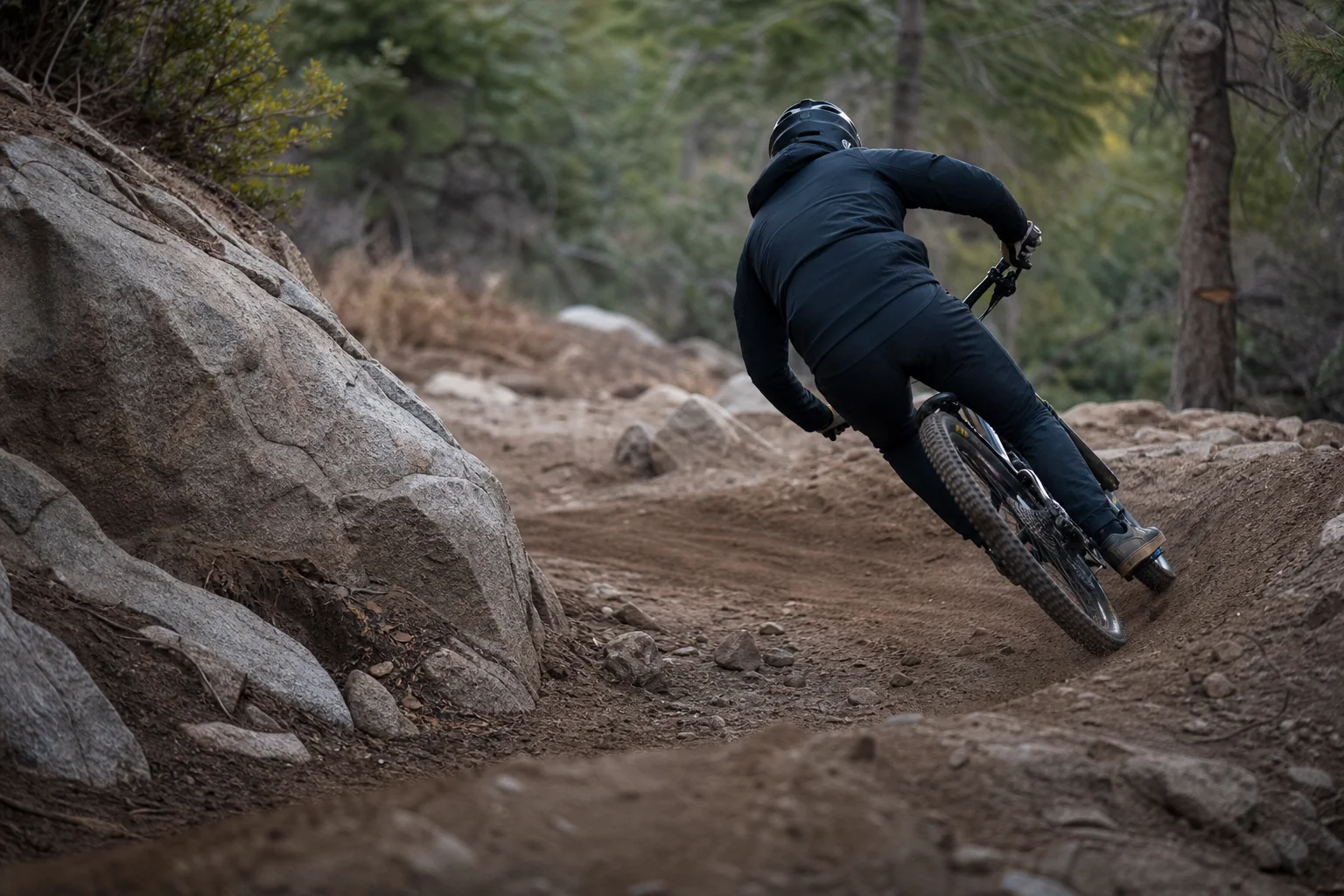 Mountainbiker fährt durch eine enge Kurve auf einem Trail mit Erde und Steinen