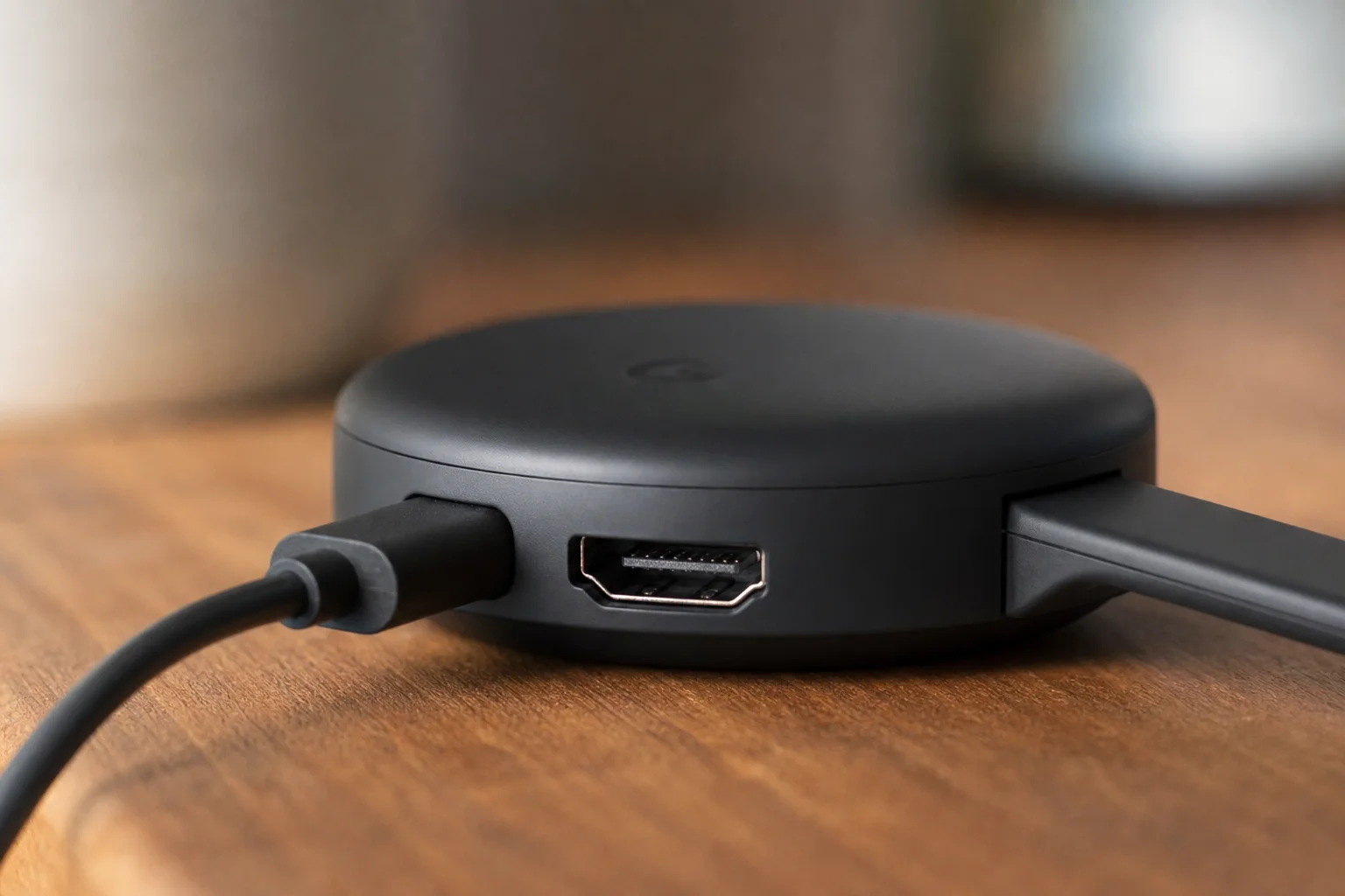Primo piano del connettore HDMI e del cavo di alimentazione di un dispositivo di streaming su una scrivania in legno