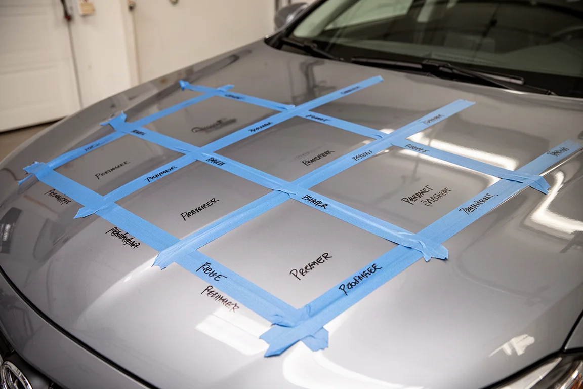 Car hood divided into test sections with tape and permanent marker labels