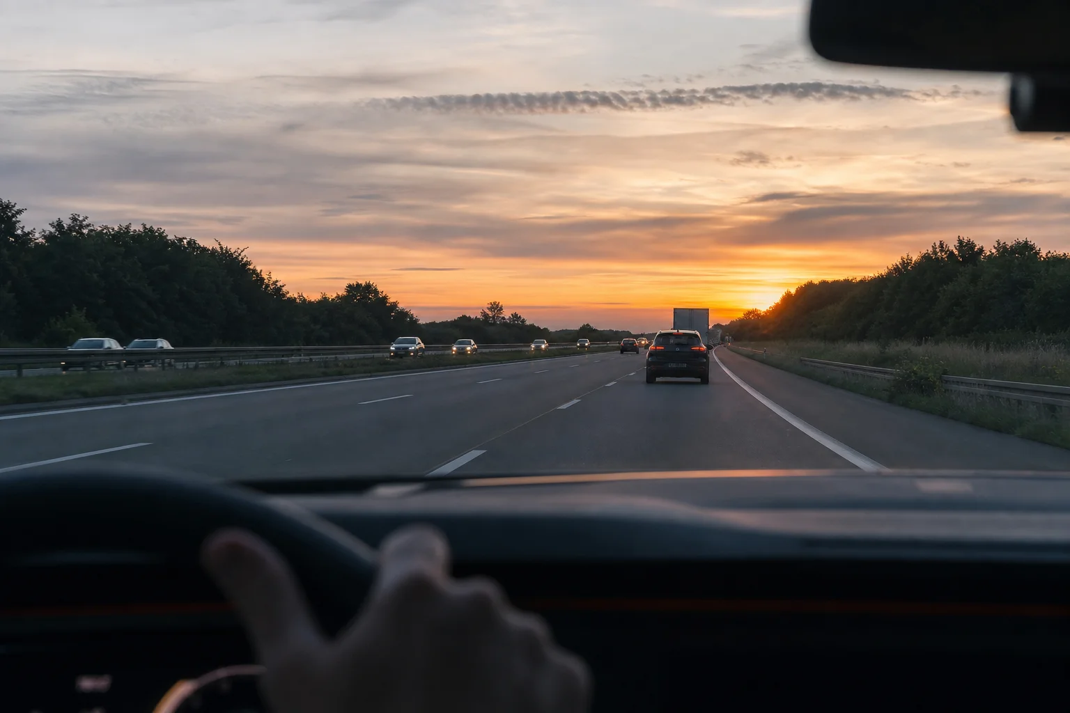Autobahn in der Dämmerung mit Fahrzeugarmaturenbrett und Straße voraus