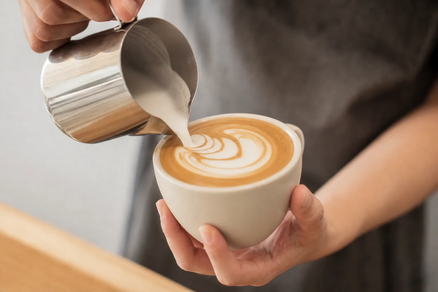 Barista pouring steamed milk into espresso for latte art
