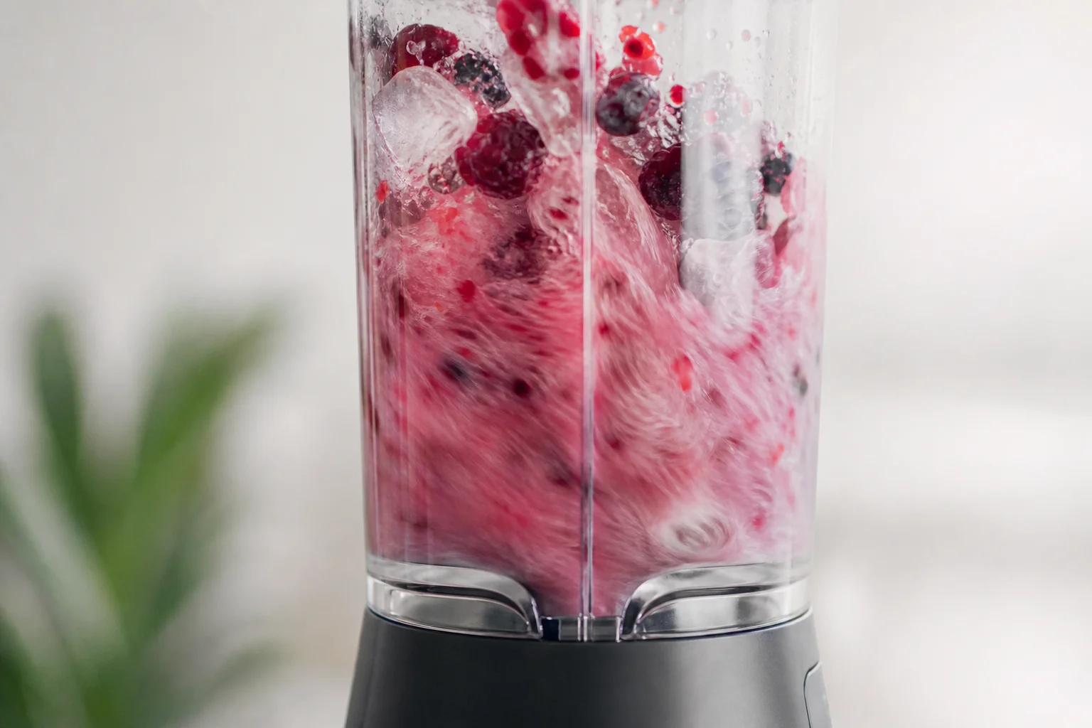 Close-up of blender crushing ice and frozen berries with motion