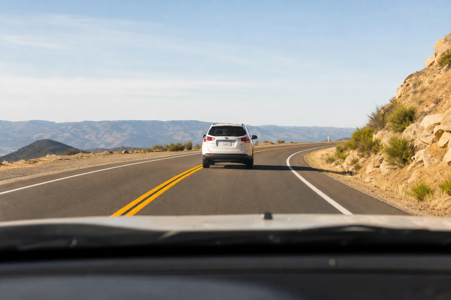 Dashboard view through windshield showing road ahead with clear license plate visibility