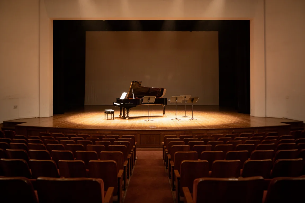 Sala de concerto vazia vista de uma fileira central com iluminação de palco quente