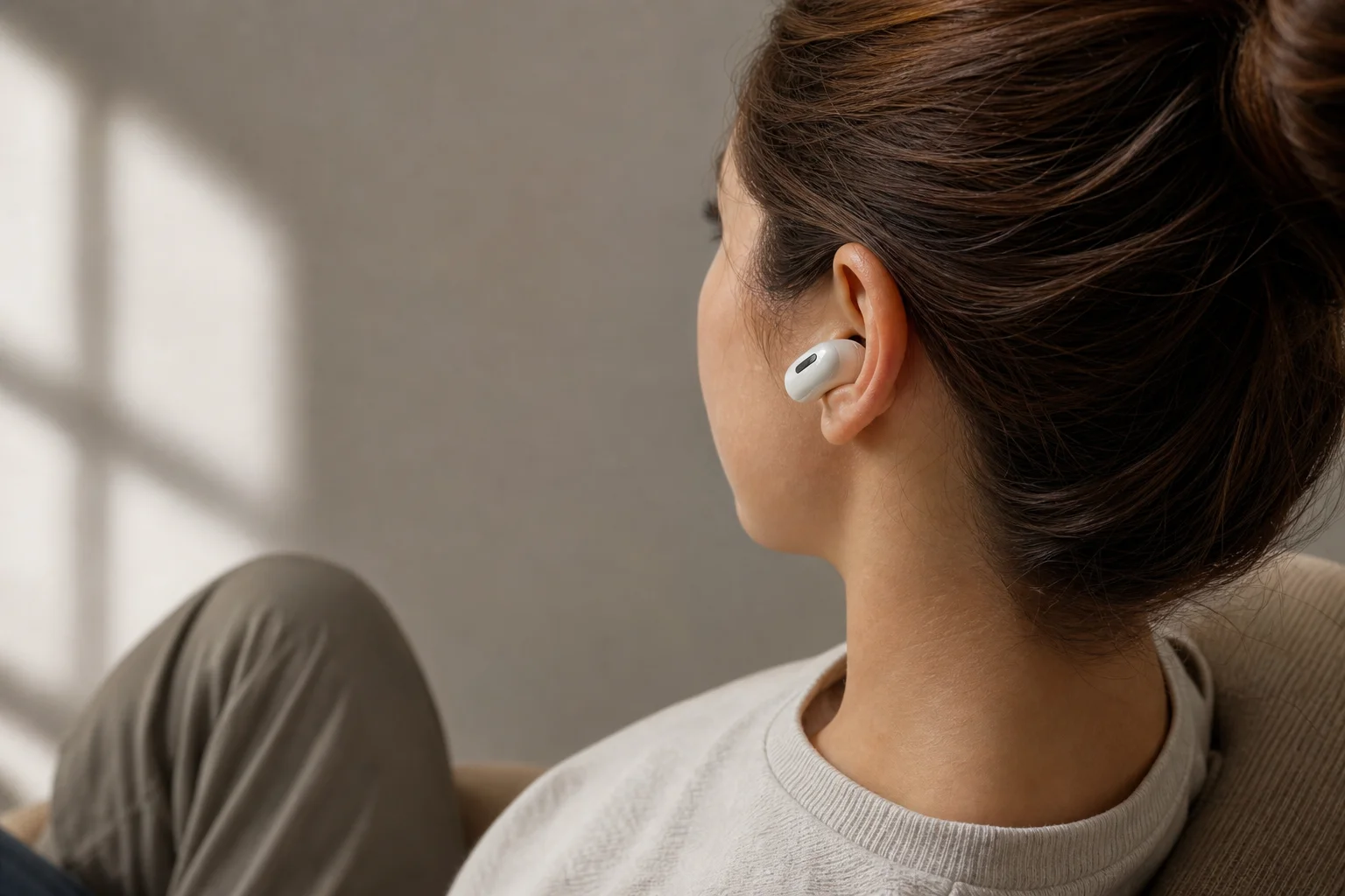 Person trägt In-Ear-Kopfhörer in einer bequemen Sitzposition in Innenräumen