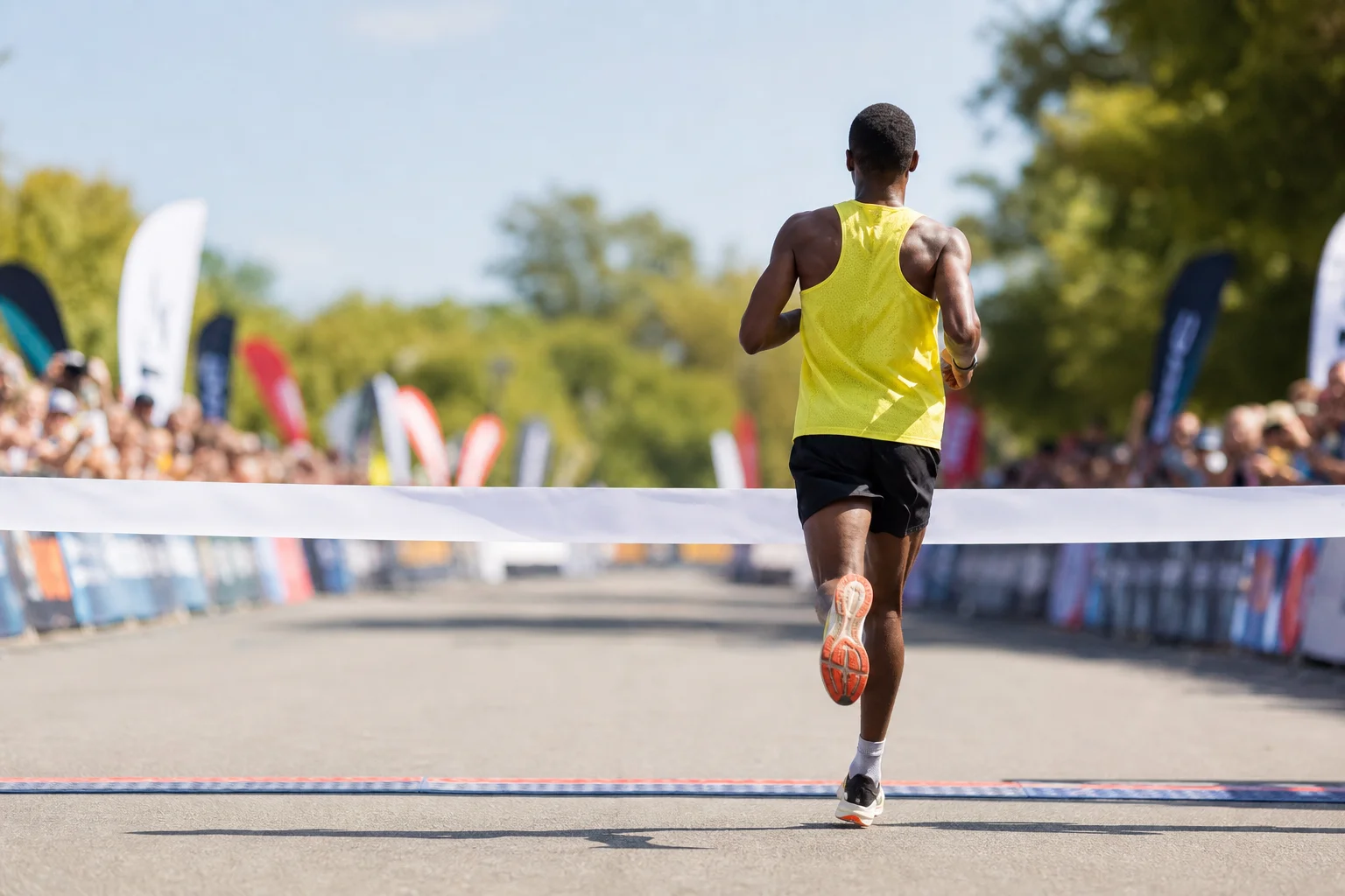 Marathon runner crossing finish line in bright daylight
