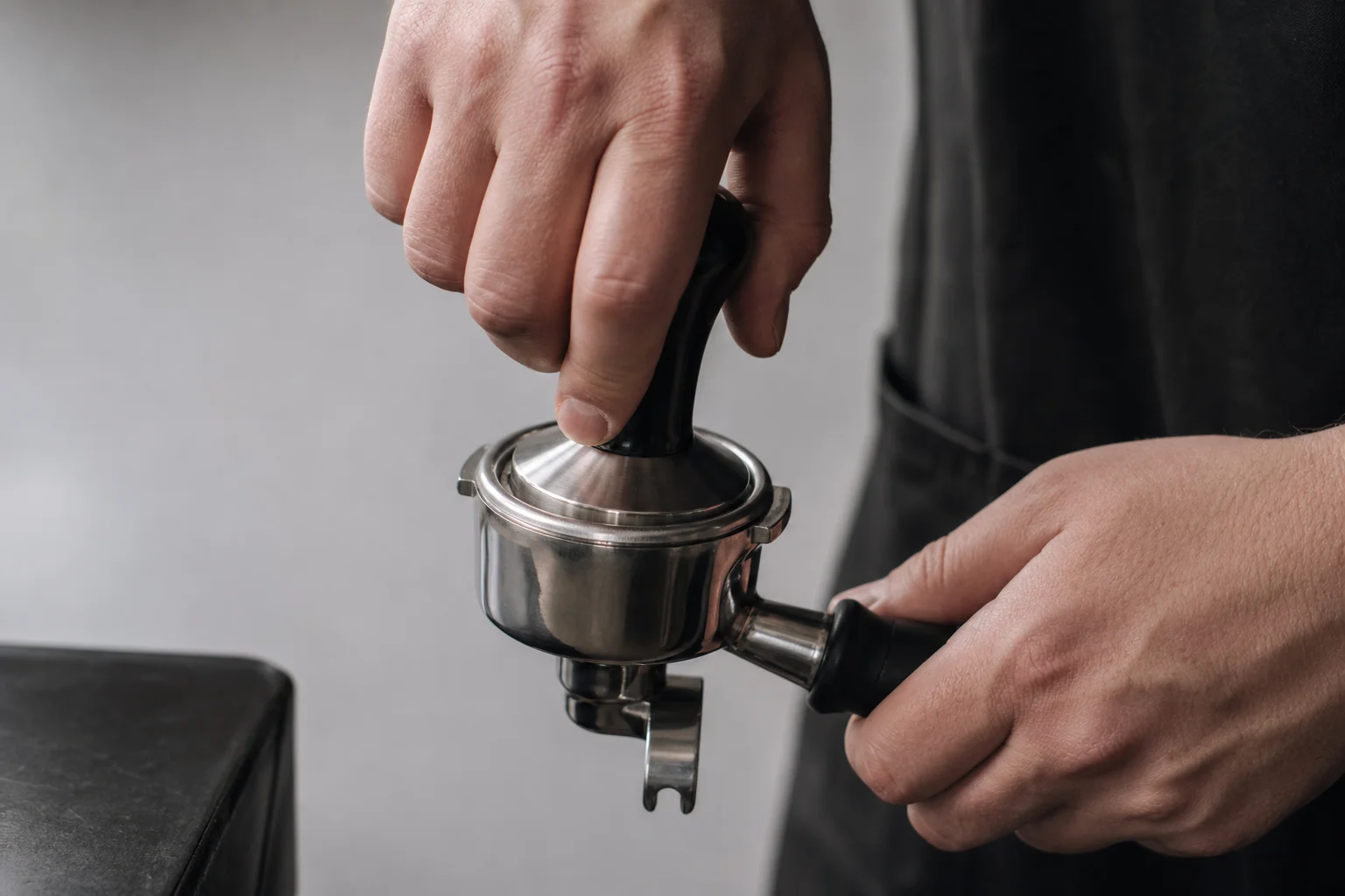 Barista tamping espresso grounds in portafilter with precision