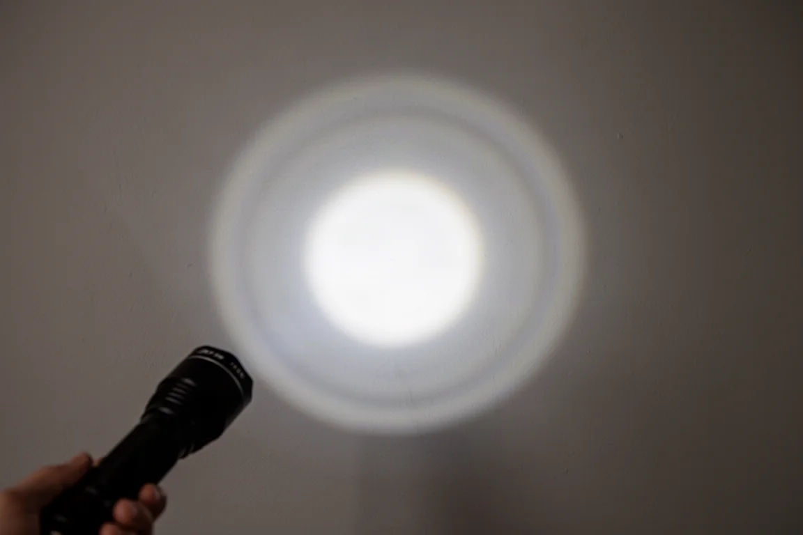 Flashlight beam pattern on a white wall showing a bright hot spot and softer spill