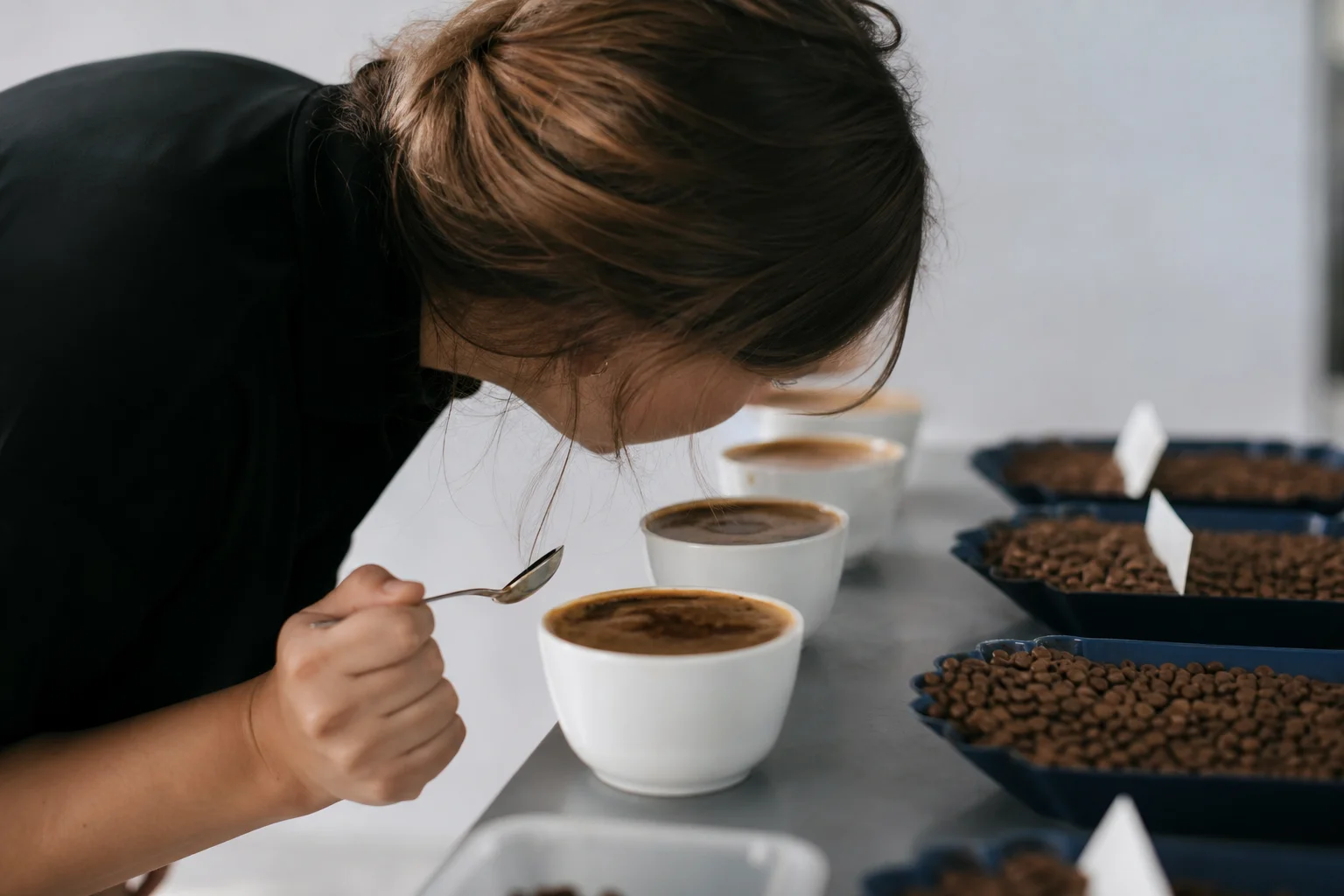 Person evaluating coffee aroma from a tasting cup