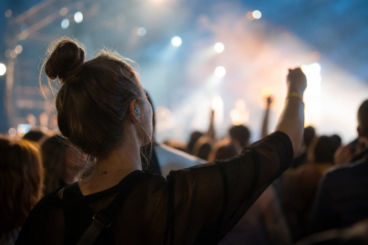 Person in a concert venue enjoying music while wearing filtered earplugs