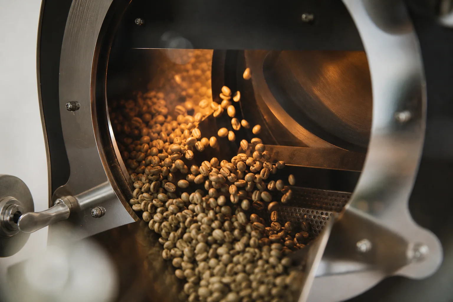 Green coffee beans roasting inside a drum chamber with warm light