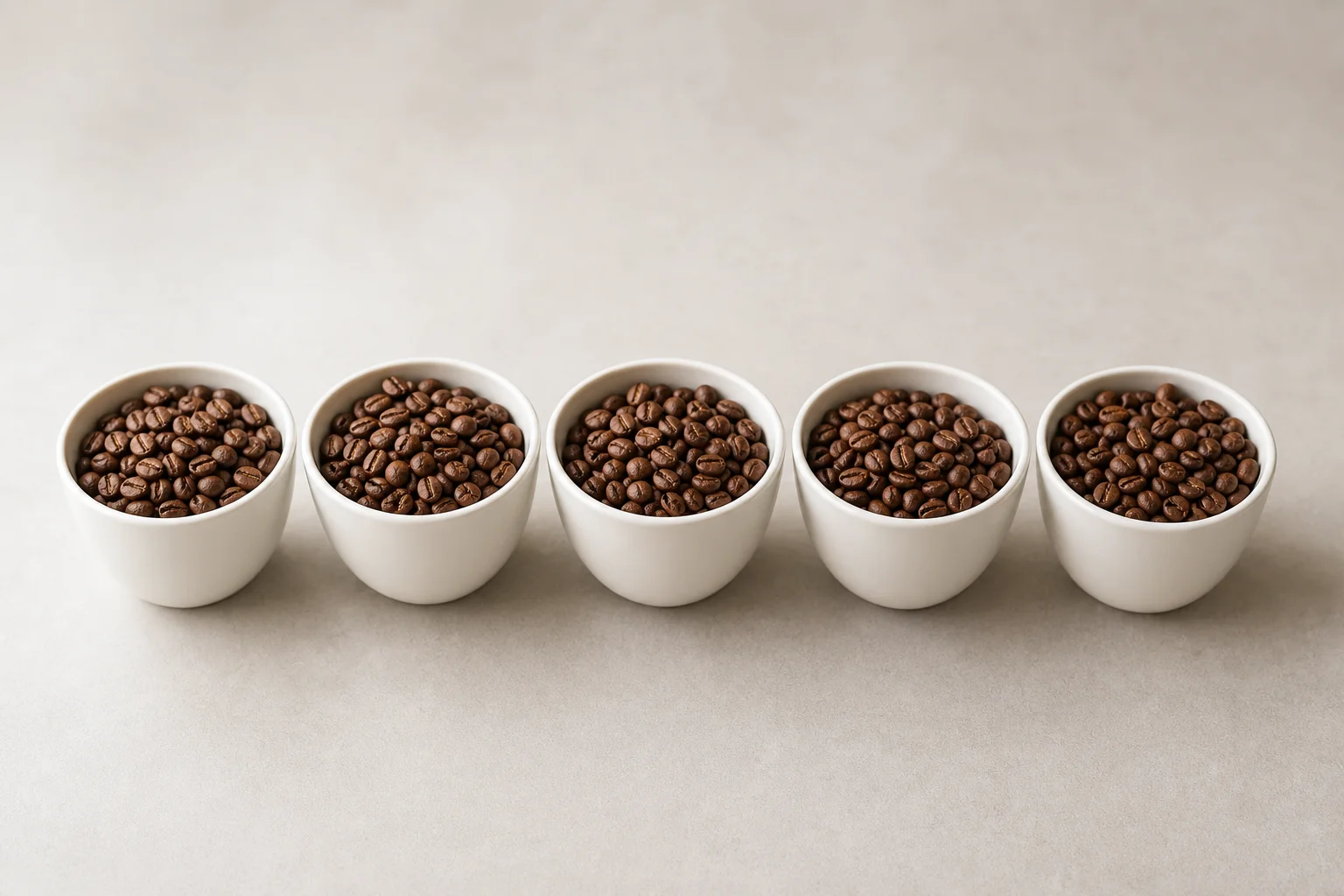 Five roasted coffee samples in cups showing consistent city-plus roast color