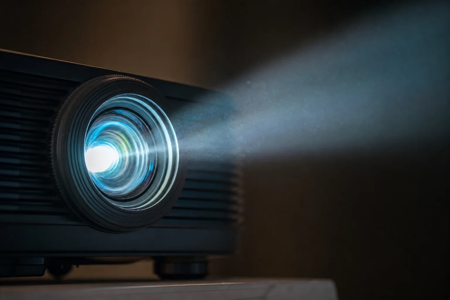 Obiettivo di un proiettore con fascio di luce visibile in una stanza buia