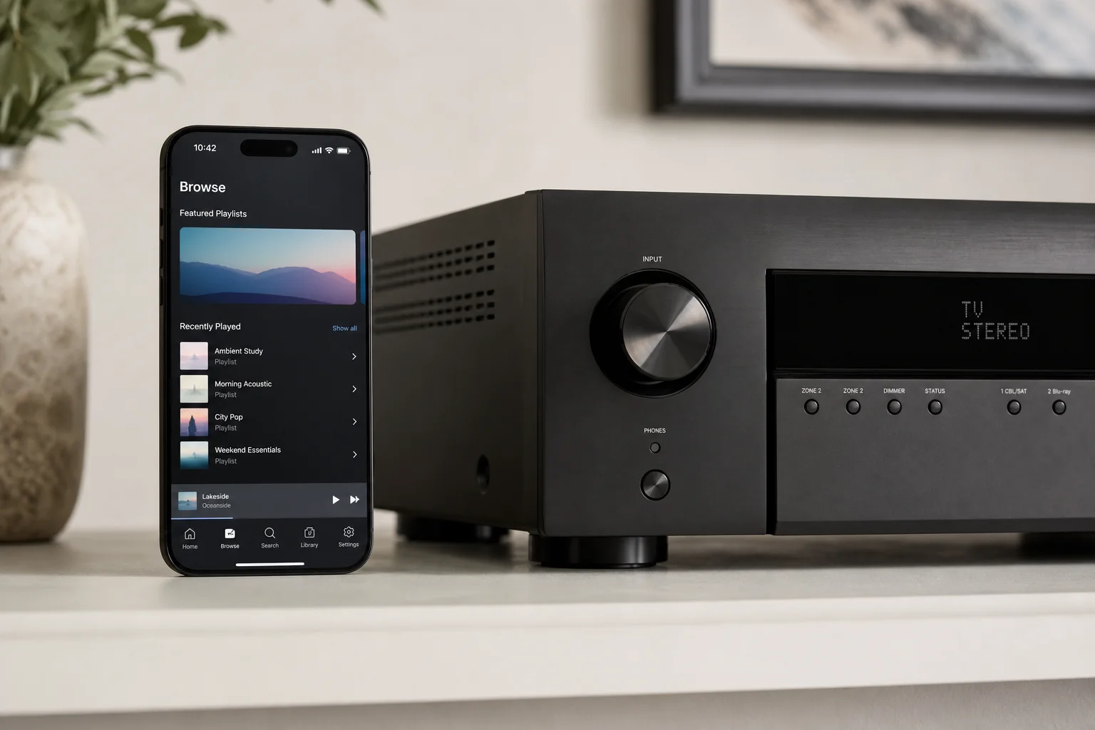 Smartphone che mostra un'app di streaming musicale accanto a un sintoamplificatore home theater