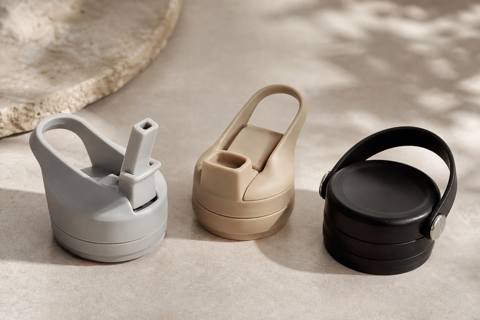 Three bottle lids with different designs displayed on neutral surface
