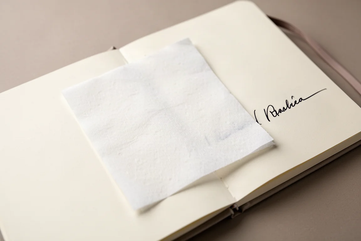 Hoja de papel secante junto a la página abierta de un cuaderno con tinta fresca